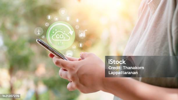 Industrial Emissions Pollute The Environment And Ecology Including Climate Change Carbon Reduction Agreement From Renewable Energy Reduce Greenhouse Gas Emissions Young Woman Looking At Smartphone Stock Photo - Download Image Now