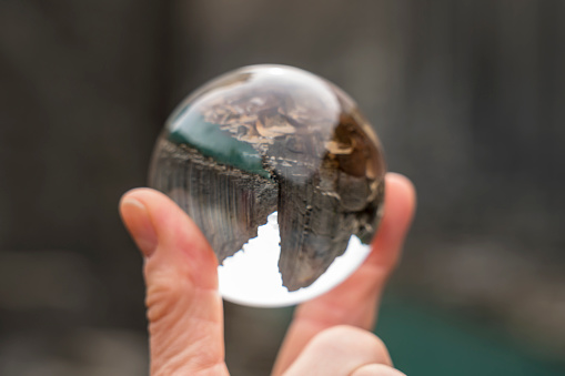 Basalt columns in Studlagil canyon mirroring in crystal ball in female hand, Jokuldalur Valley.