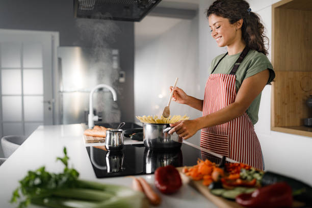 istock Happy woman enjoying while cooking spaghetti for lunch. 1421211375