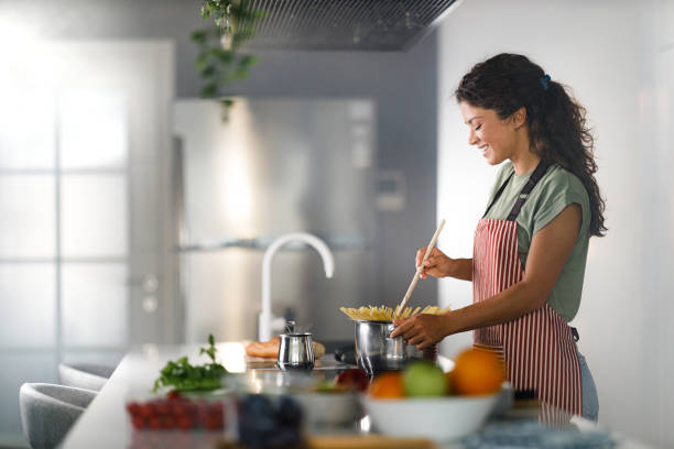 istock Young happy woman making spaghetti in the kitchen. 1421211669