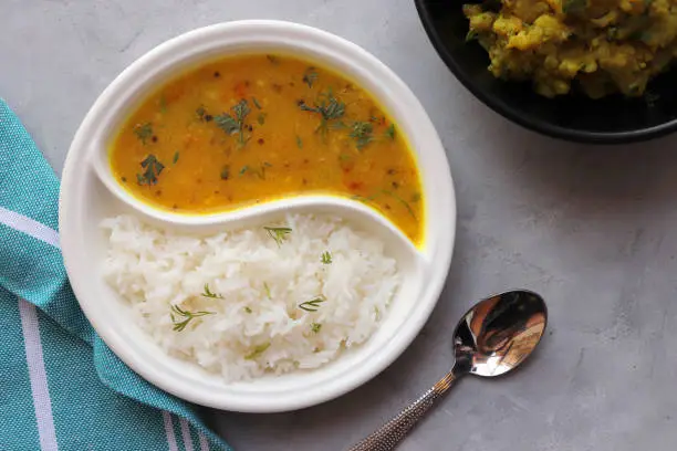 Healthy nutritious Indian comfort food Dal Chawal thali or Dal Rice. Served in two way ceramic plate. Over white background with copy space.