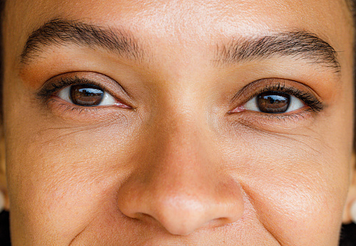 Close up of African American woman with brown eyes looking at camera.