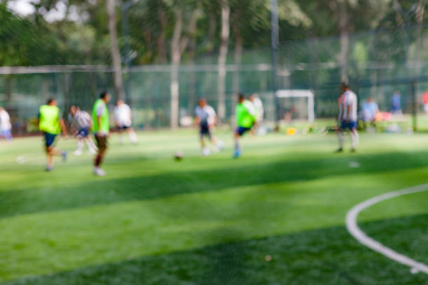 gente pateando la pelota en el campo de fútbol en el parque, fuera de foco - american football football focus on foreground team sport fotografías e imágenes de stock