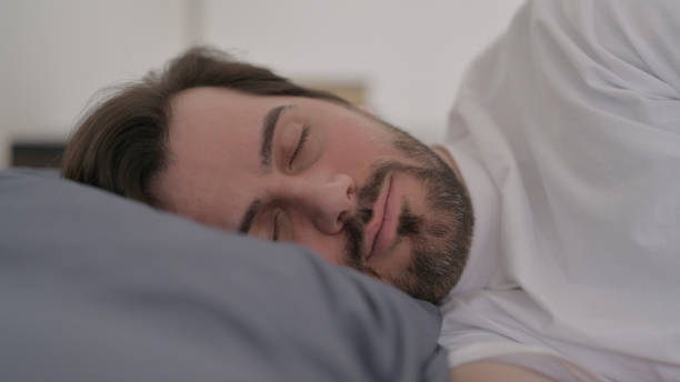 istock Portrait of Young Man Sleeping in Bed Peacefully 1421215462