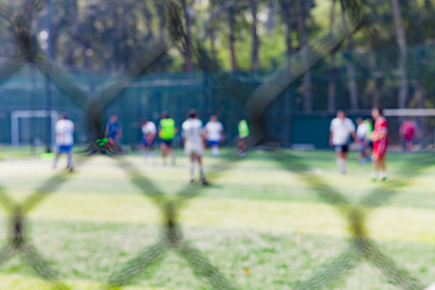 les gens frappent le ballon sur le terrain de football dans le parc, hors de propos - american football football focus on foreground team sport photos et images de collection