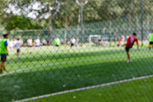 les gens frappent le ballon sur le terrain de football dans le parc, hors de propos - american football football focus on foreground team sport photos et images de collection