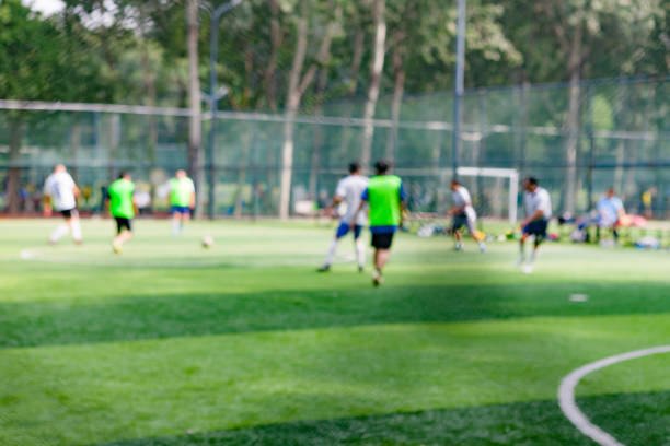 gente pateando la pelota en el campo de fútbol en el parque, fuera de foco - american football football focus on foreground team sport fotografías e imágenes de stock