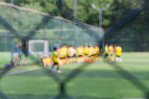 des gens qui tapent dans le ballon sur le terrain de soccer dans le parc, hors de propos - american football football focus on foreground team sport photos et images de collection