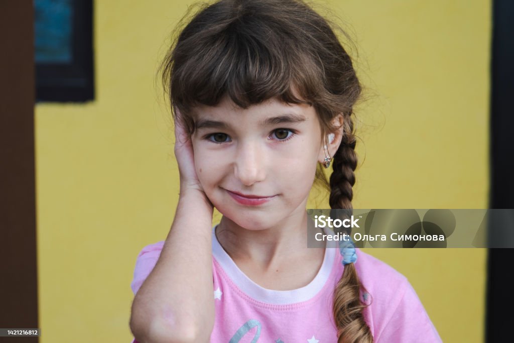 Girl with a warming therapeutic cotton swab in the ear with a sad and tearful face is holding her ear. Ear pain, otitis media, swelling of cheek, gums, toothache, children's surgery, otolaryngology Child Stock Photo