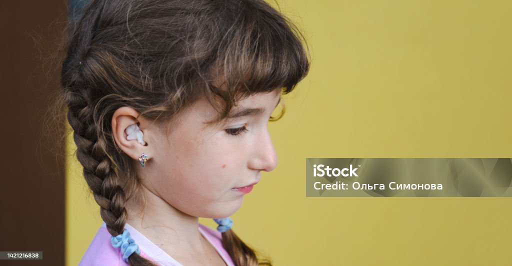 Girl with a warming therapeutic cotton swab in the ear with a sad and tearful face is holding her ear. Ear pain, otitis media, swelling of cheek, gums, toothache, children's surgery, otolaryngology 4-5 Years Stock Photo