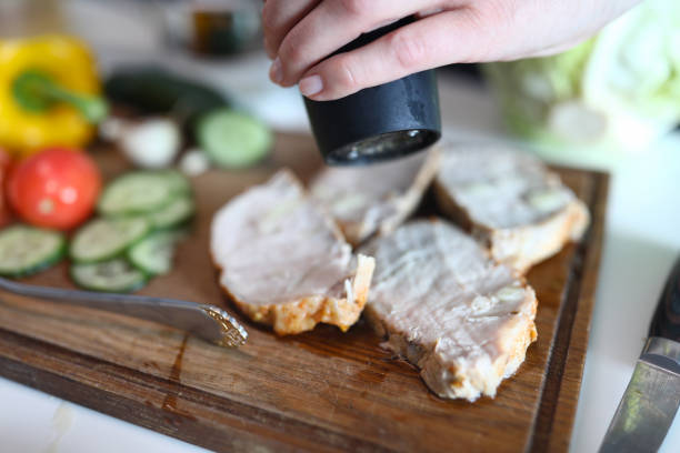 Meat bacon pork or veal cooked by chef hands on wooden board. Adding spices cooking meat concept