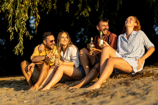 Group of friends sitting on beach and talking