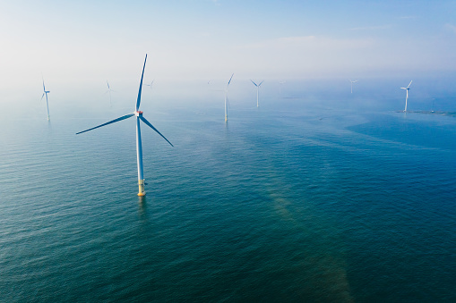 Wind turbine. Aerial view of wind turbines or windmills farm field in blue sea in Finland. Sustainable green clean energy.