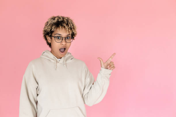 istock Surprised African American woman pointing copy space 1421223129
