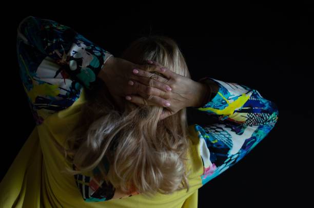istock Woman on black background with hands behind her head 1421224485