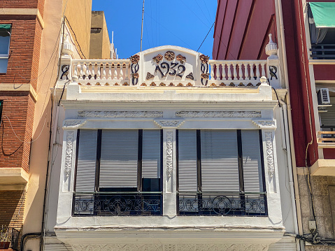 Valencia, Spain - July 8, 2022: Old renovated house between two new modern buildings in the Cabanyal district. This neighborhood has lots of old houses dating from the first half of the 20th century