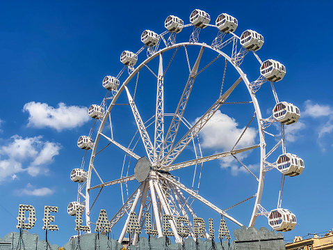 Valencia, Spain - July 8, 2021: Low angle view of ferris wheel in summer amusement park. Every year one is set at the Turia Garden so children can enjoy their holidays