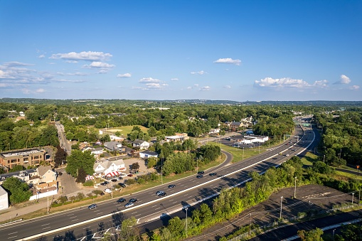 An aerial shot of a residential area with cars driving on the road and buildings and trees in the background