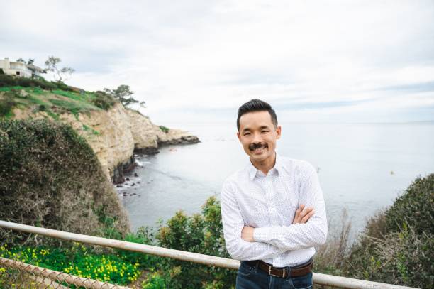 heureux homme d’affaires japonais asiatique debout sur fond de mer à san diego - on top of business cliff businessman photos et images de collection