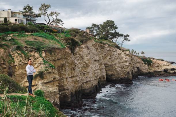 hombre de negocios asiático japonés de pie en el borde de un acantilado cerca de la orilla del mar en san diego - on top of business cliff businessman fotografías e imágenes de stock