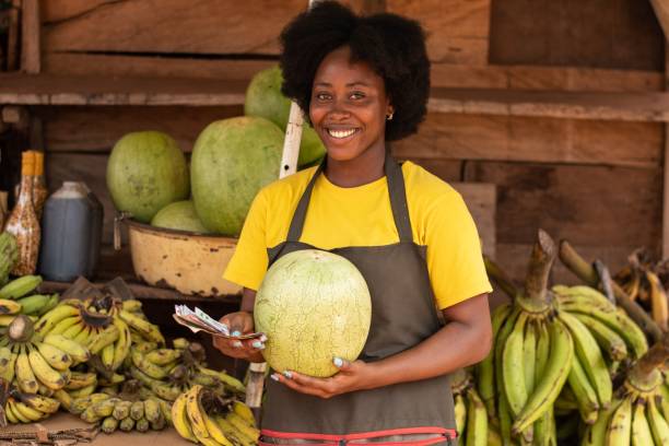 dame, die eine wassermelone und geld auf einem markt hält - country market stock-fotos und bilder