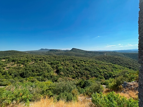 Natural summertime landscape on the arid , rough French south Mediterranean Gard with trees, stones, hills and blue sky