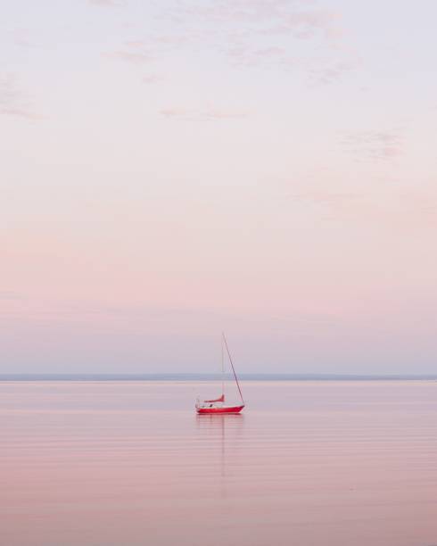 A vertical shot of a sail boat during pink sunset
