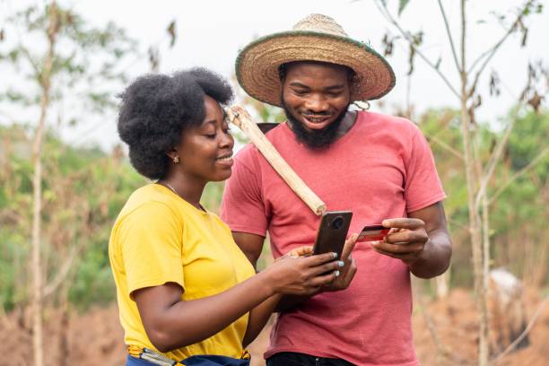 happy african farmers using a phone and credit card excited african farmers using a phone and credit card mobile payment photos stock pictures, royalty-free photos & images