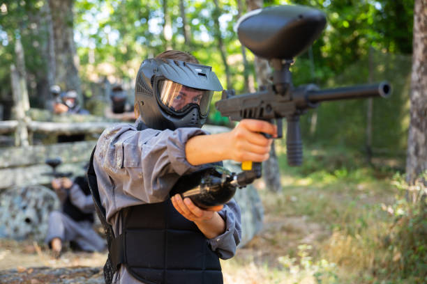 istock Paintball player in protective uniform aiming and shooting with guns 1421232042
