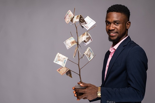 african man holding a plant with money as leaves