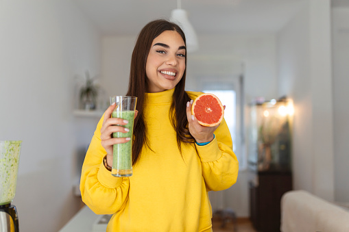 Beautiful woman holding glass of smoothie and grapefruit. Healthy lifestyle. Raw food diet, vegetarian nutrition, organic detox meal