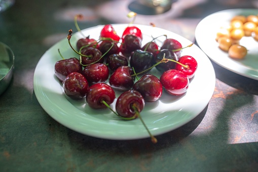 A closeup of red cherries on a white plate at a restaurant