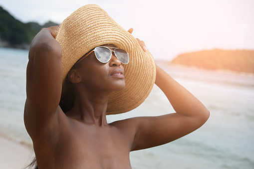 Beautiful african woman wear a hat with sunglasses in bikini enjoying summer vacation on beach