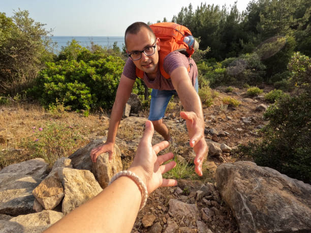 istock Girlfriend Helping Boyfriend Climb Up The Mountain 1421239640