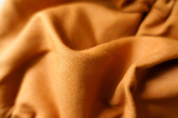 istock Soft folds on brownish orange hemp and cotton fabric 1421241018