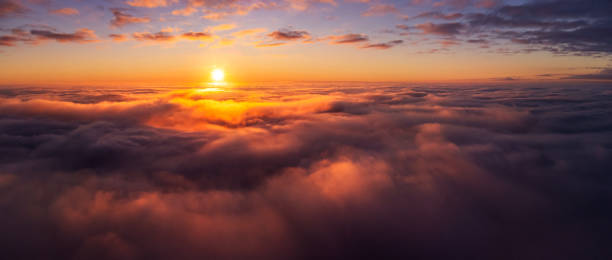 Majestic photo above the clouds of setting sun under horizon stock photo