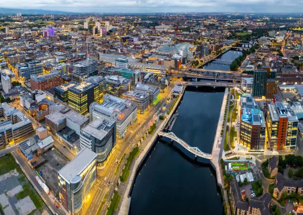 Glasgow United Kingdom aerial shot of modern buildings in the central area of the city with river and squigly bridge in the foreground in twilight