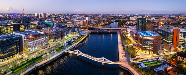 Glasgow United Kingdom aerial shot of modern buildings in the central area of the city with River Clyde and squigly bridge in the foreground by night
