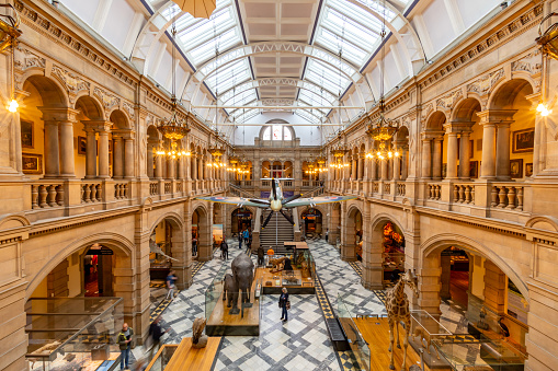 Glasgow United Kingdom interior view of the Kelvingrove Art Galery and Museum a free to enter for the public with people viewing the exhibits including a spitfire hanging in the room