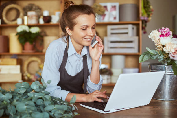 istock Pretty woman working at flower shop, using technology 1421245795
