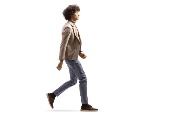 Full length profile shot of a tall man with a curly hair walking stock photo