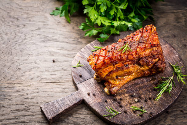 Roasted pork belly with crust and herbs on cutting board