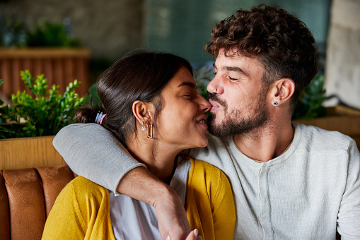 Profile photo of mixed race couple in love face each other, pout lips and going to kiss, close eyes from pleasure, dressed in stylish clothes, have date, over pink background. Romantic relationships.