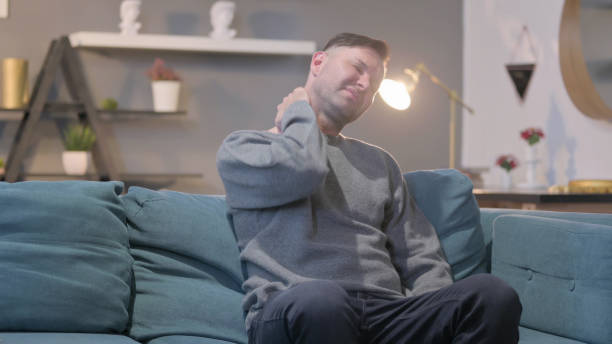istock Casual Man having Neck Pain while Sitting on Sofa 1421254498