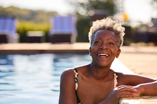 Portrait Of Smiling Senior Woman On Summer Holiday Relaxing In Swimming Pool