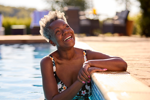 Smiling Senior Woman On Summer Holiday Relaxing In Swimming Pool