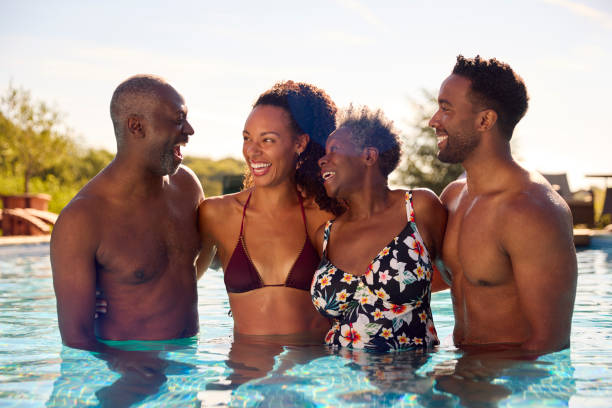 família multigeracional com filhos adultos nas férias de verão relaxando na piscina juntos - swimming swimming pool senior adult child - fotografias e filmes do acervo