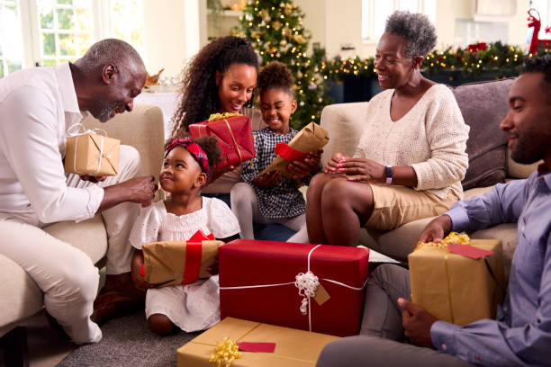 famiglia multi-generazione che festeggia il natale a casa aprendo i regali insieme - grandmother giving gift child foto e immagini stock
