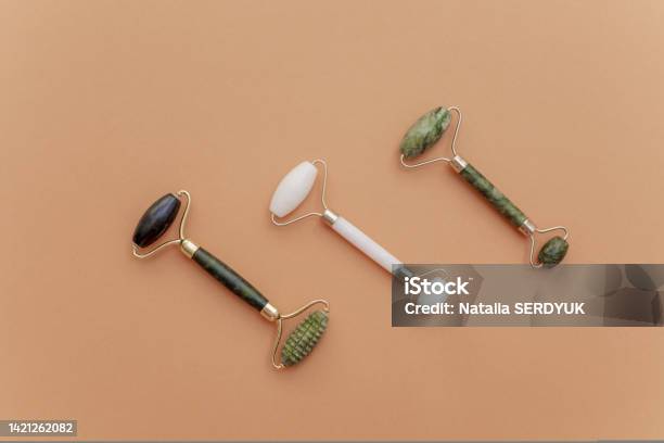 Green And White Jade Roller For Facial Massage On Stones On A Beige Background Three Natural Rejuvenating Massage Products For Lymphatic Drainage And Wrinkle Smoothing Beauty And Personal Care Accessoriesminimalistic Scene Stock Photo - Download Image Now