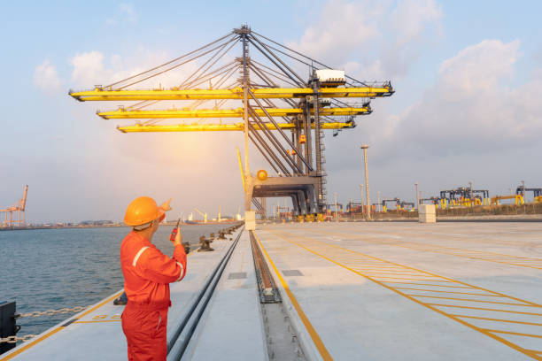 istock Foreman control loading container by crane at international container sea port , Service man check crane and call radio communication cocept logistic service transportation. 1421262149
